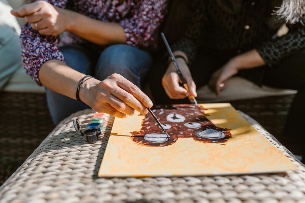 pexels-photo-7104138-7104138 Adults enjoying a creative painting session outdoors, focusing on art and bonding.